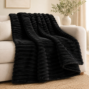 Black chunky ribbed plush blanket throw on a sofa